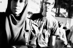 The image is a black and white photograph of a man and a woman standing next to each other