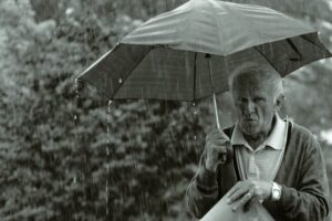 Main Subject: Man with umbrella Visual Elements: The man is holding a black umbrella and appears to