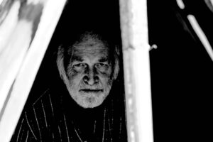 Main Subject: Old man in a tent Visual Elements: Darkness, the silhouette of a man, and an old-fashi