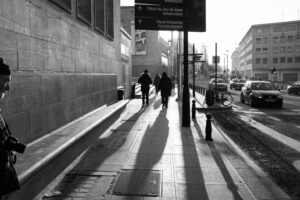 Main Subject: The main subject of the image is a person walking on a sidewalk at dawn